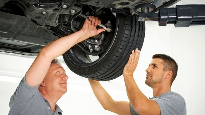 Mechanics inspecting ball joint clearance